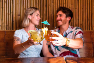 male and female cheers with tropical tiki drinks