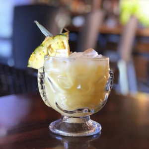 tropical drink with a pineapple wedge on a wooden table