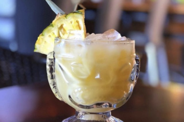 tropical drink with a pineapple wedge on a wooden table